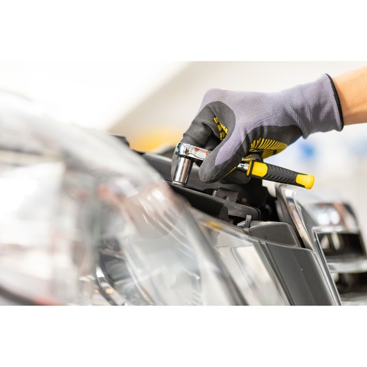 STANLEY STMT86104-0 ratchet wrench used for car repair, close-up photography with gloved hand.