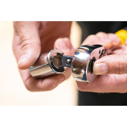 Photo of STANLEY STMT86510-0 ratchet wrench with socket held in hand, close-up view.