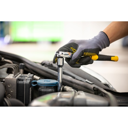 Photo of STANLEY STMT88942-0 ratchet wrench used for automotive repair, gloved hand holding tool over engine.