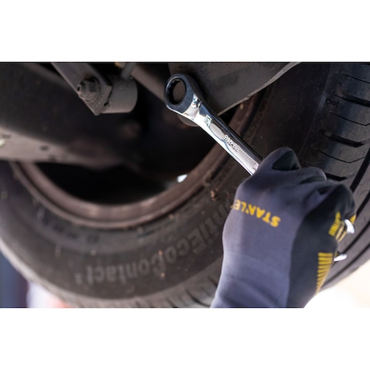 STANLEY STMT89913-0 ratcheting wrench in use on vehicle wheel, close-up photography.