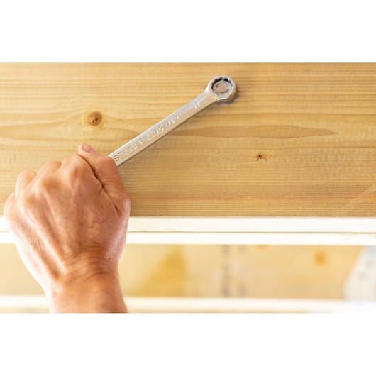 STANLEY STMT95788-0 ratcheting wrench in use on a wooden beam, close-up view.