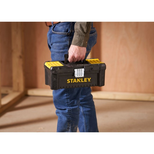 STANLEY STST1-75515 black and yellow toolbox held by person in work site, side view.