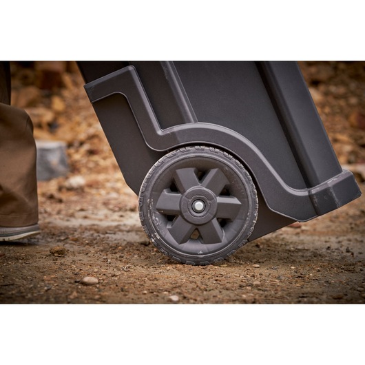 STANLEY STST1-79231 photography of black wheeled tool box wheel on rough outdoor surface.