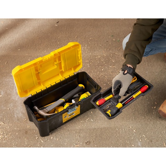 STANLEY STST75785-1 tool box with open lid, showing hand lifting tray with assorted hand tools on workshop floor.