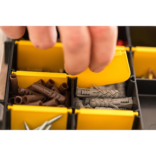 STANLEY STST81680-1 organizer box with yellow compartments, containing screws and wall plugs, close-up view.