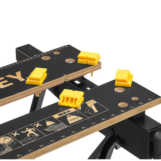 STANLEY STST83400-1 workbench top view with yellow clamps, rulers, and safety icons on black surface.