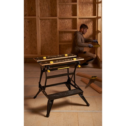 STANLEY STST83800-1 workbench with black frame and yellow accents in a workshop setting.