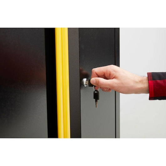 STANLEY STST97595-1 cabinet with yellow trim, close-up of lock and hand turning key, product photography.