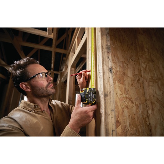 Photo of STANLEY XTHT0-33501 tape measure used to measure wooden frame during construction.