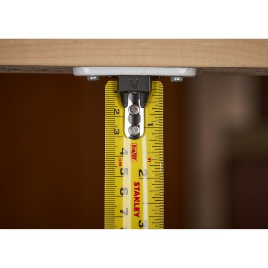 STANLEY XTHT0-33504 tape measure close-up showing metric markings and hook under wood, product photography.
